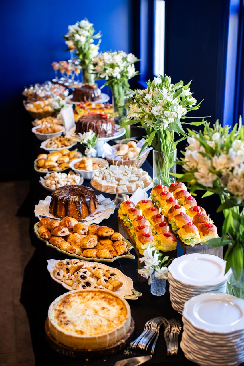 Mesa de coffee break completa com quiches, salgados e bolos